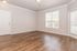 Bright and airy living room with elegant hardwood floors, neutral walls, and large windows providing abundant natural light.
