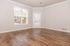 Bright and inviting living room with elegant wooden flooring, large window, and door leading to a private outdoor space.