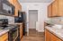 Modern kitchen with sleek black appliances, warm wood cabinets, and elegant countertops opening to a convenient laundry area.
