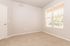 Bright and inviting apartment bedroom with plush carpeting and large window providing ample natural light.
