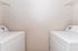 Chic laundry room with modern washer and dryer, featuring ample shelving for convenient storage.