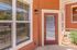 Inviting apartment exterior with elegant red siding, large windows, and a modern glass door leading to a cozy patio area.