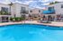 Modern apartment complex featuring a sparkling pool, sun loungers, and charming balconies, perfect for relaxed outdoor living.