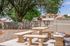 Serene outdoor patio with elegant stone benches and tables set beneath lush trees, offering a perfect spot for relaxation in a charming residential area.