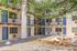 Inviting apartment complex courtyard featuring modern architecture, balconies with sleek railings, and a communal stone picnic table surrounded by natural landscaping.
