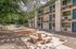 Charming apartment complex with vibrant blue doors, balconies, and a serene outdoor seating area surrounded by lush trees.