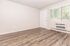 Bright and inviting room with modern wood flooring, large window with blinds, and new wall-mounted air conditioning unit.
