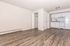 Chic open-concept apartment with modern laminate flooring, bright white kitchen, and ample closet space.