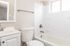 Bright and modern bathroom with a sleek bathtub, elegant white vanity, and natural light from a large window.
