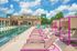Vibrant poolside retreat featuring colorful lounge chairs, modern amenities, and lush greenery under a sunny blue sky.