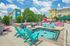 Vibrant outdoor pool area with colorful lounge chairs and modern apartment buildings in the background, perfect for relaxation.