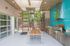 Chic outdoor dining area featuring a sleek barbecue station with vibrant turquoise tiles and a modern wooden table set under skylights.