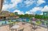 Vibrant rooftop terrace with colorful seating, overlooking a sunny courtyard and surrounded by lush greenery.