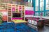 Chic entertainment area with vibrant accents featuring a pool table, stylish bar with purple stools, modern shelving, and large windows for natural light.