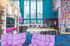 Vibrant and modern lounge with high ceilings, colorful decor, and stylish seating; featuring a sleek kitchen area and a pool table for entertainment.