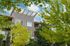 Modern apartment building framed by lush greenery and a bright blue sky, showcasing stylish architecture and ample natural light.