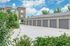 Modern apartment complex boasting sleek garages surrounded by lush greenery under a vibrant blue sky.