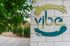 Inviting entrance sign of Vibe Apartments with lush landscaping and modern design.