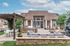 Charming apartment exterior with a welcoming patio, comfortable seating, and elegant pergola under a clear sky.