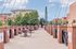 Charming urban walkway with brick accents, outdoor seating, and lush greenery, perfect for leisurely strolls and community gatherings.