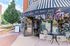 Charming café entrance adorned with vibrant flowers and elegant outdoor seating, inviting atmosphere for a cozy experience.