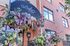 Charming brick building adorned with vibrant floral arrangements under a stylish tea room sign, creating a lively and inviting atmosphere.