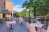 Charming outdoor patio with pink chairs and marble tables, surrounded by lush greenery and vibrant flowers, perfect for alfresco dining.