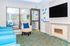 Bright and modern sitting room with stylish blue chairs, cozy fireplace, elegant decor, and a large window offering a scenic outdoor view.