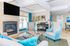 Bright and inviting living space featuring elegant blue armchairs, a modern fireplace, and a sleek piano with vibrant decor accents.