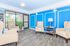 Bright and inviting lounge area featuring elegant armchairs, vibrant blue accent walls, and large windows offering lush outdoor views.