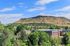 Majestic hillside view overlooking a vibrant residential neighborhood with lush greenery, perfect for serene living.