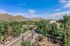 Scenic view of a vibrant town nestled in lush greenery with majestic mountains in the background under a clear blue sky.