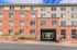 Modern brick apartment building with large windows and welcoming entryway, set against a vibrant blue sky.