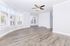 Spacious and bright living area with elegant hardwood flooring, large windows, and a modern ceiling fan, perfect for cozy family gatherings.