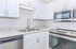 Modern kitchen with sleek stainless steel appliances, elegant white cabinetry, and granite countertops.