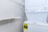 Modern laundry room with energy-efficient washer and dryer stack, accompanied by spacious shelving.