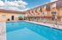 Inviting apartment complex with a sparkling outdoor pool, sun loungers, and stylish seating area under a bright blue sky.