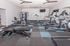 Modern fitness center with state-of-the-art equipment including treadmills, exercise bikes, and a multifunctional gym machine in a spacious, well-lit room.
