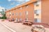 Charming apartment building with inviting outdoor picnic area and natural rock accents, perfect for enjoying sunny days.