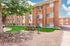 Charming apartment complex with warm exterior tones, lush green lawn, and inviting picnic area under a large tree.