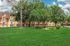 Charming apartment building surrounded by lush green lawns and mature trees, offering scenic views and a tranquil setting.