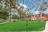 Charming apartment complex with lush green lawn, mature trees, and a welcoming community ambiance.