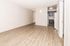 Spacious apartment interior featuring elegant wood flooring and modern kitchen area with sleek cabinetry.
