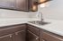 Modern kitchen corner with sleek silver faucet, elegant dark wood cabinets, and a stunning light fixture.
