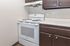 Modern kitchen corner featuring a sleek white electric stove and elegant dark brown cabinets, creating a stylish and functional cooking space.