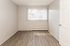 Bright, cozy empty room with sleek wood floors and ample natural light from a large window, perfect for a personalized touch.