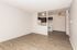 Modern living space featuring elegant wood floors, cozy kitchen with dark cabinets, and stylish ceiling fan, ideal for open-concept living.