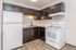 Modern kitchen with sleek dark wood cabinetry, elegant white appliances, and stylish lighting, perfect for culinary enthusiasts.