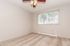Bright and airy bedroom with lush carpet, modern ceiling fan, and large window offering delightful natural light.