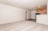 Bright and airy living space with plush carpet, modern kitchen with wooden cabinets, and elegant ceiling fan for ultimate comfort.